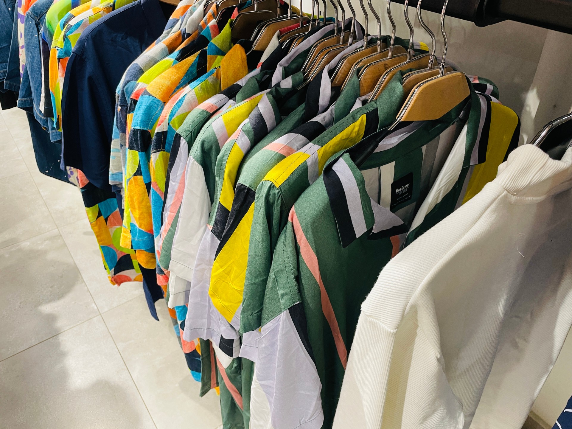 Shirts dress shirts colourful apparels hanging on hangers on display of a cloth store